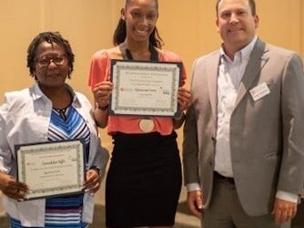 2 women holing certificates and man in suit